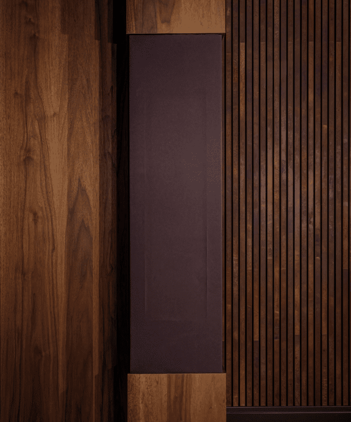 Een glad donker paneel tussen een houten wand met verticale latten en een paneel met een natuurlijke houtnerf. Een glad donker paneel tussen een houten wand met verticale latten en een paneel met een natuurlijke houtnerf.