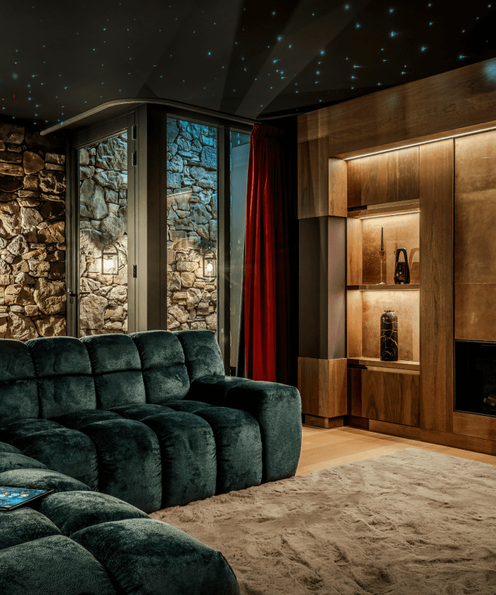 Een donkergroene bank in een luxe woonkamer met een sterrenhemelplafond, houten wandkasten en een stenen buitenmuur. Een donkergroene bank in een luxe woonkamer met een sterrenhemelplafond, houten wandkasten en een stenen buitenmuur.