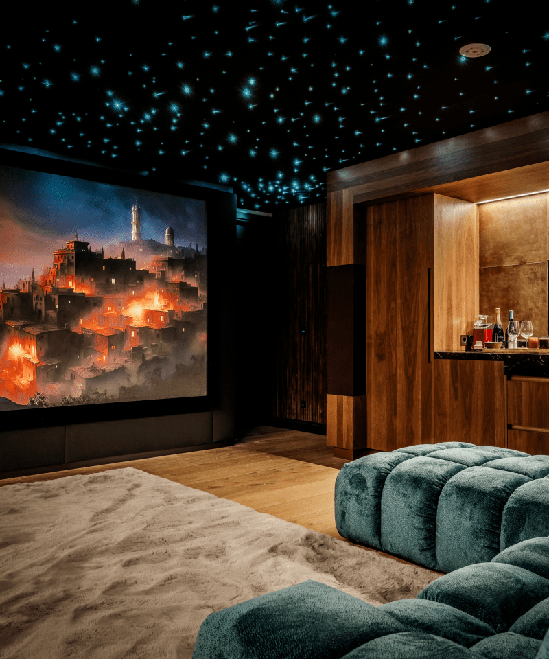 Een luxe thuisbioscoop met een sterrenhemelplafond, een groot projectiescherm en een comfortabele blauwe bank.