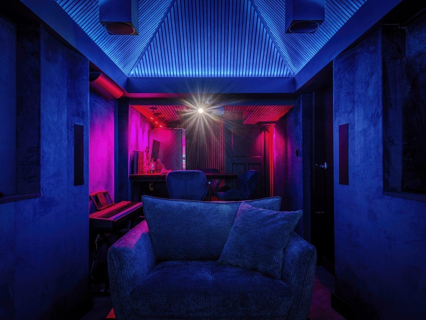 Een blauwe fauteuil in een modern verlichte kamer met paars-blauwe accentverlichting en een lichtbron in het midden. Een blauwe fauteuil in een modern verlichte kamer met paars-blauwe accentverlichting en een lichtbron in het midden.