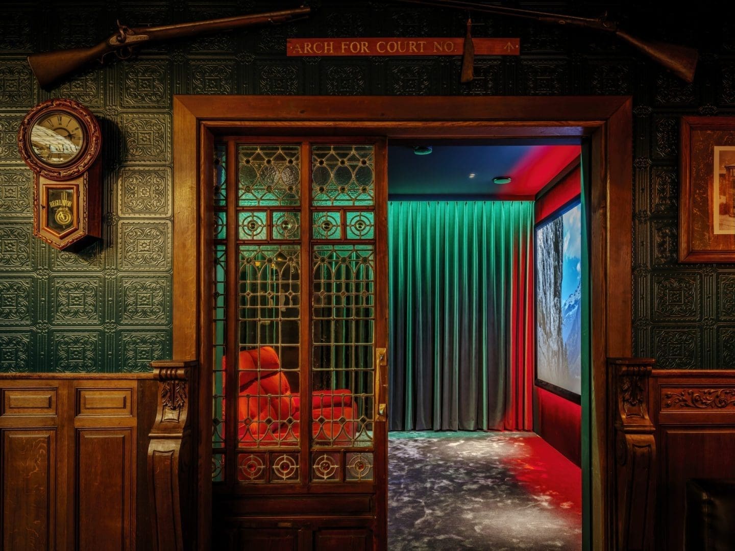 Een klassieke houten deur met glas-in-lood leidt naar een kamer met rode verlichting en gordijnen, onder een bord met tekst. Een klassieke houten deur met glas-in-lood leidt naar een kamer met rode verlichting en gordijnen, onder een bord met tekst.