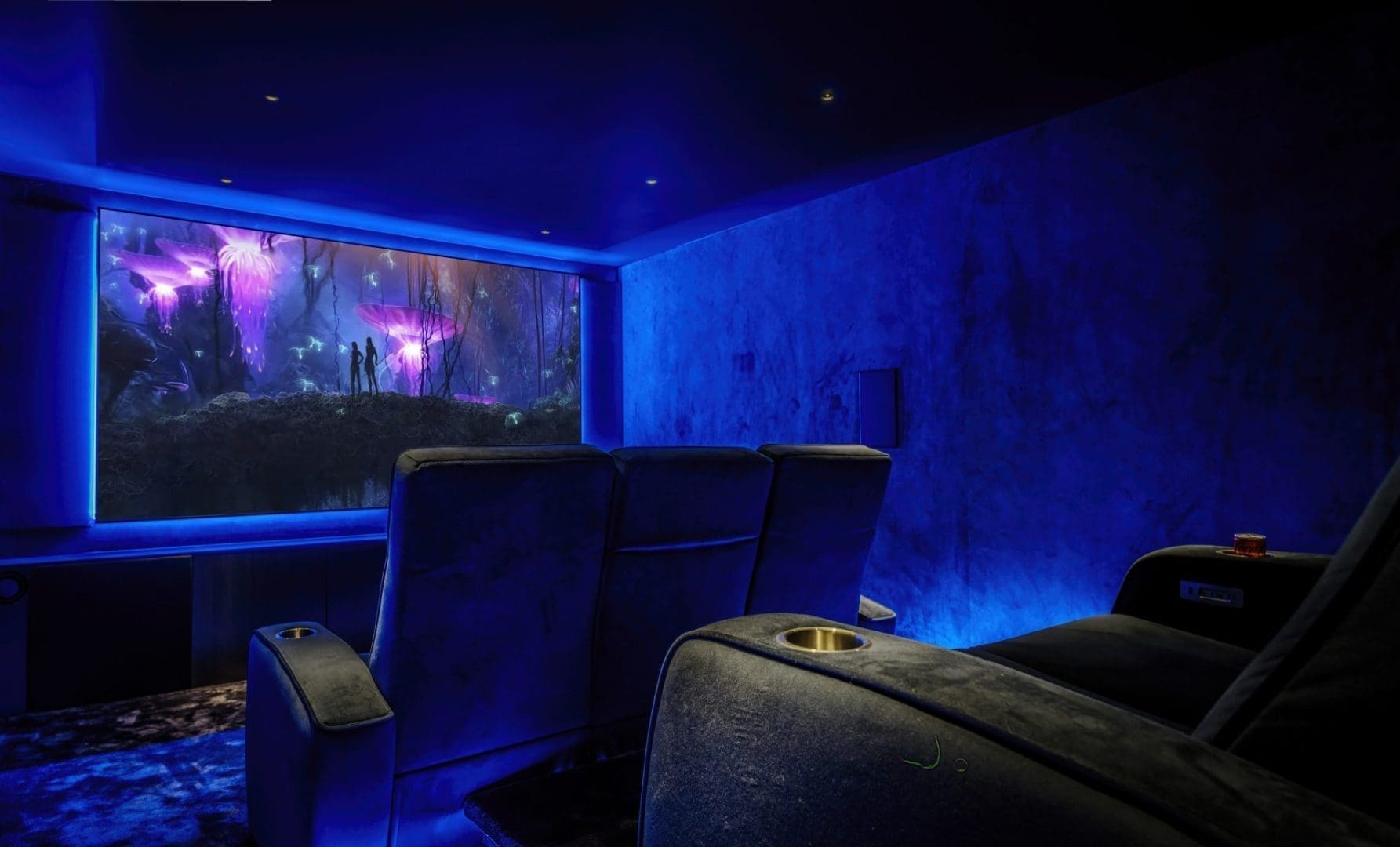 Donkere thuisbioscoop met luxe fauteuils en een groot scherm waarop een scène uit de film Avatar wordt getoond.