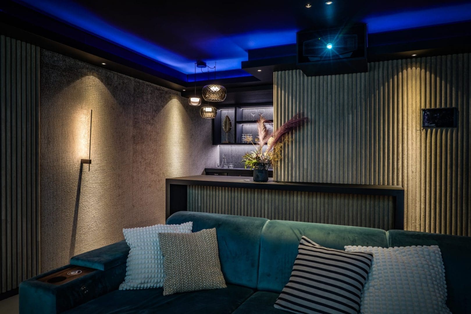 Een luxe thuisbioscoop met een blauwe fluwelen bank, sfeervolle verlichting, een bar en een plafondprojector. Een luxe thuisbioscoop met een blauwe fluwelen bank, sfeervolle verlichting, een bar en een plafondprojector.