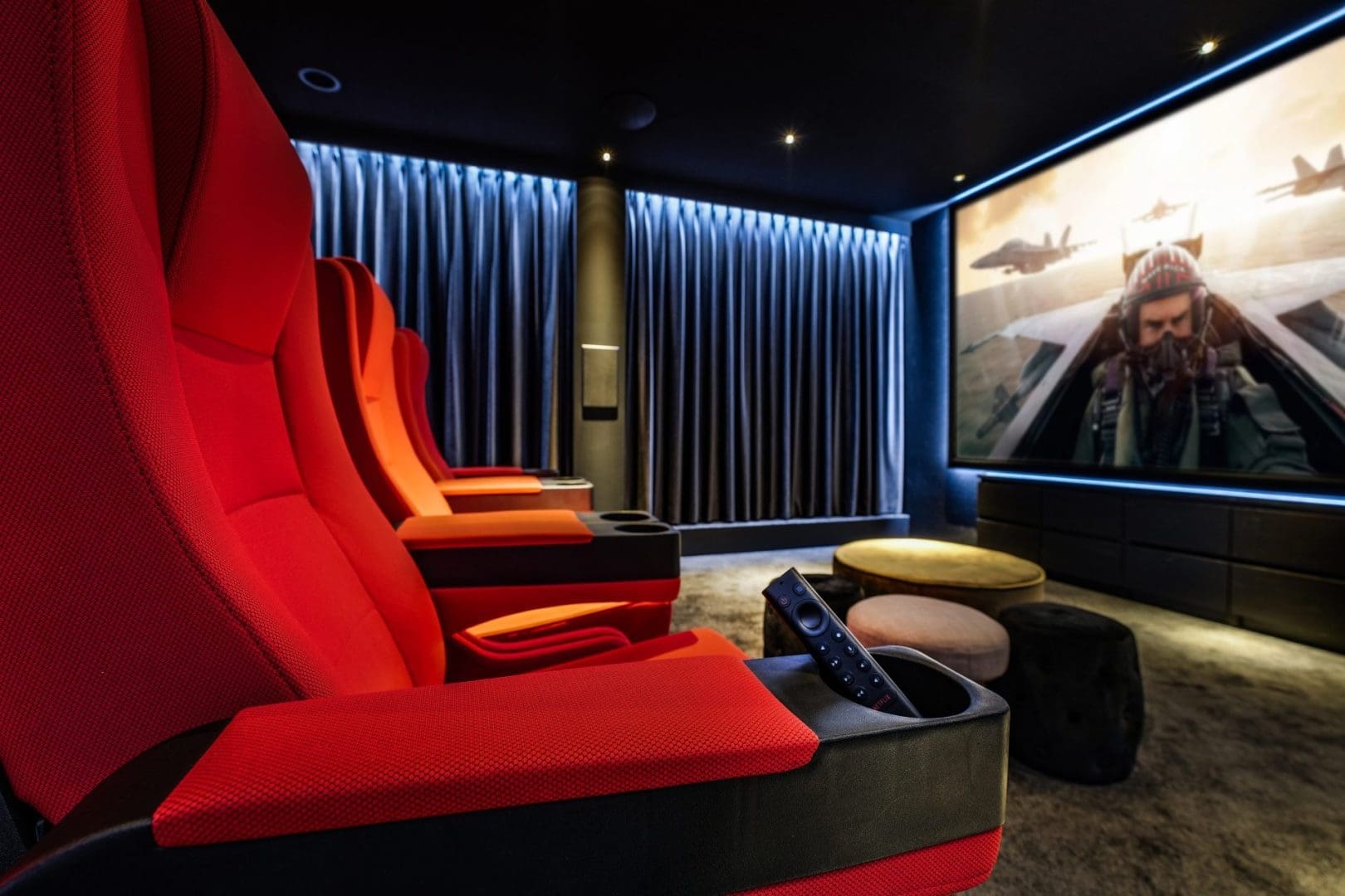 Rij met rode bioscoopstoelen in een luxe thuisbioscoop met een groot scherm waarop een gevechtspiloot te zien is. Rij met rode bioscoopstoelen in een luxe thuisbioscoop met een groot scherm waarop een gevechtspiloot te zien is.