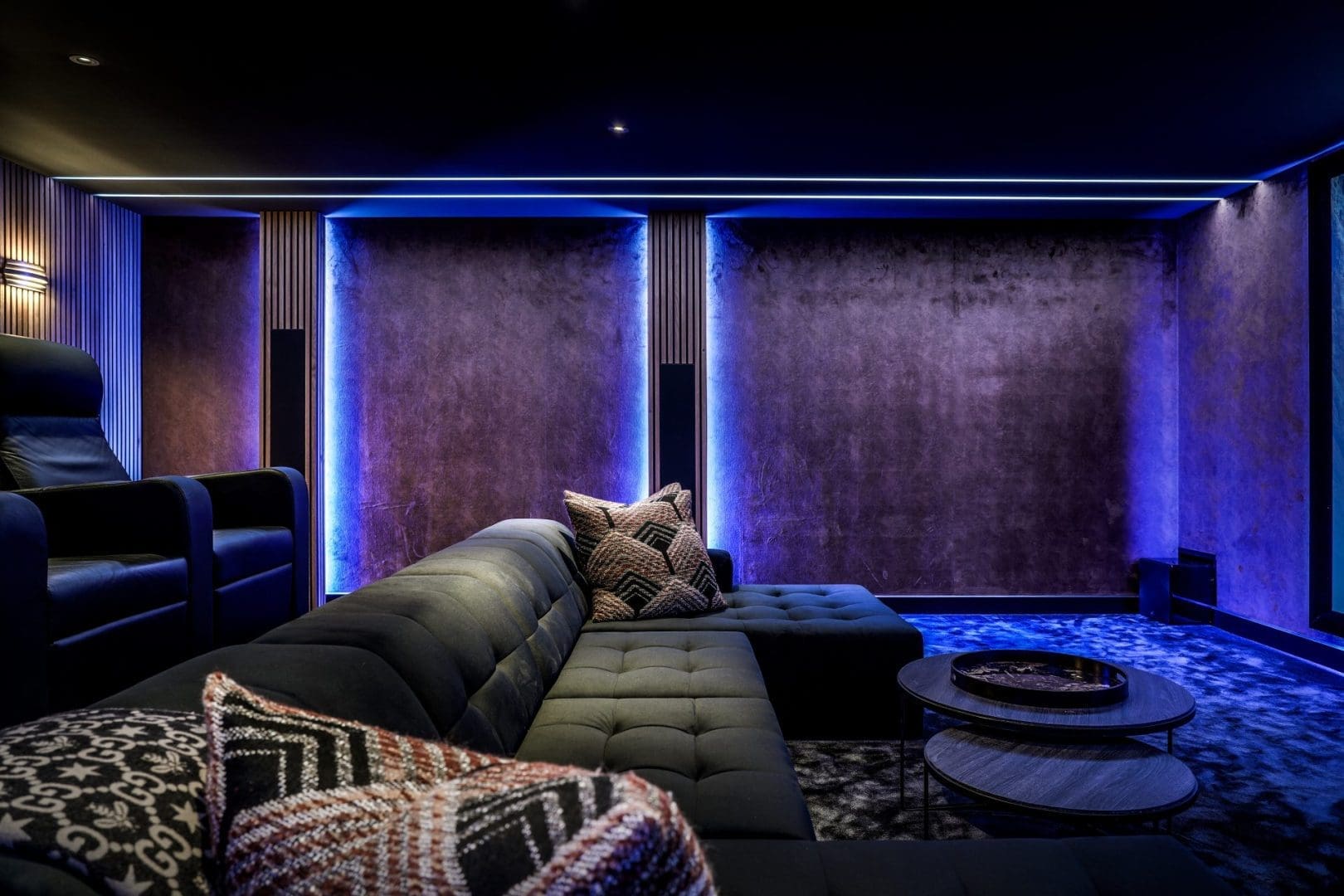 Luxe thuisbioscoop met een donkere hoekbank, fauteuils en paarse sfeerverlichting in Project Nova 0.3.