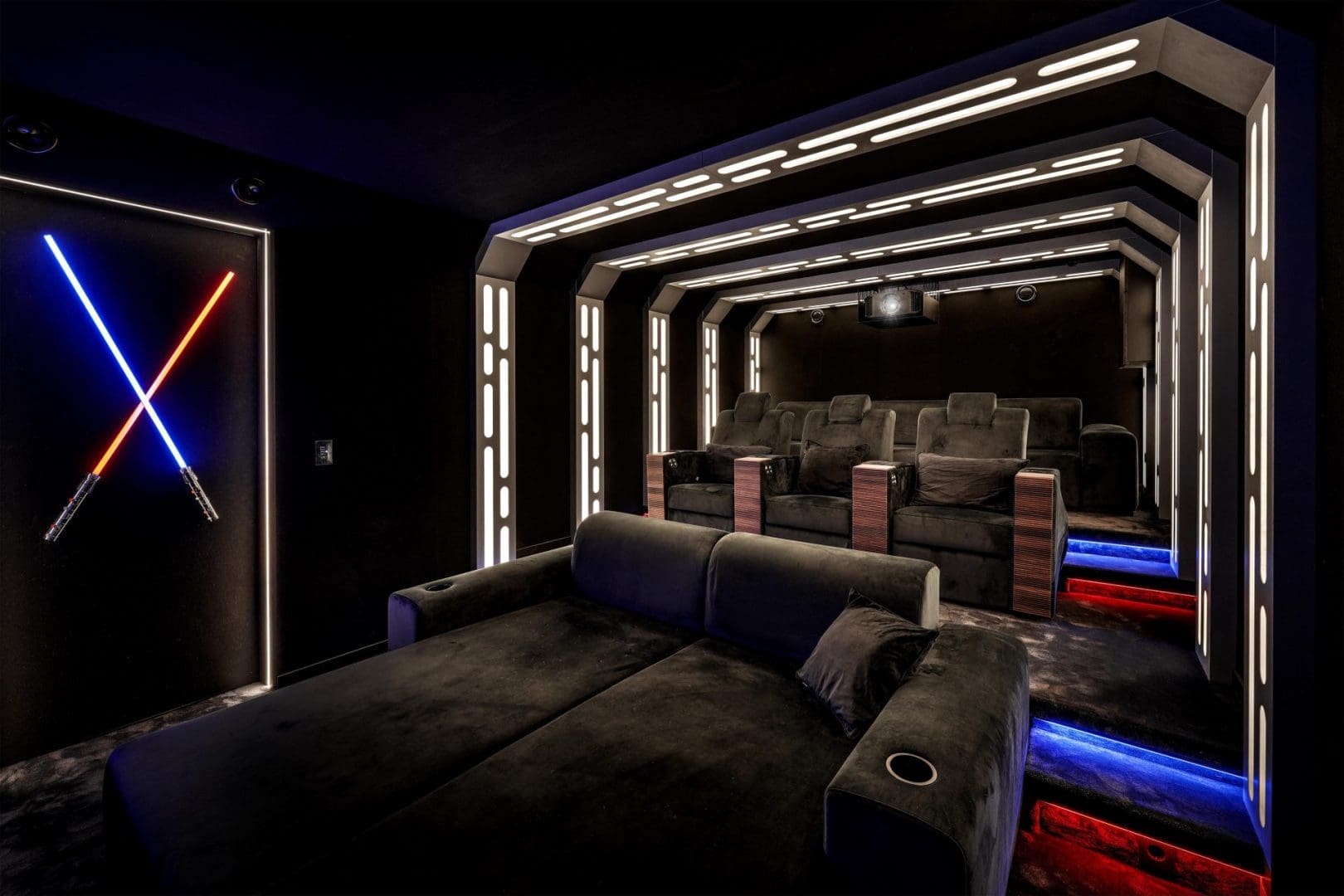 Thuisbioscoop in Star Wars-stijl met verlichte lichtzwaarden aan de muur en futuristische led-verlichting in het plafond.