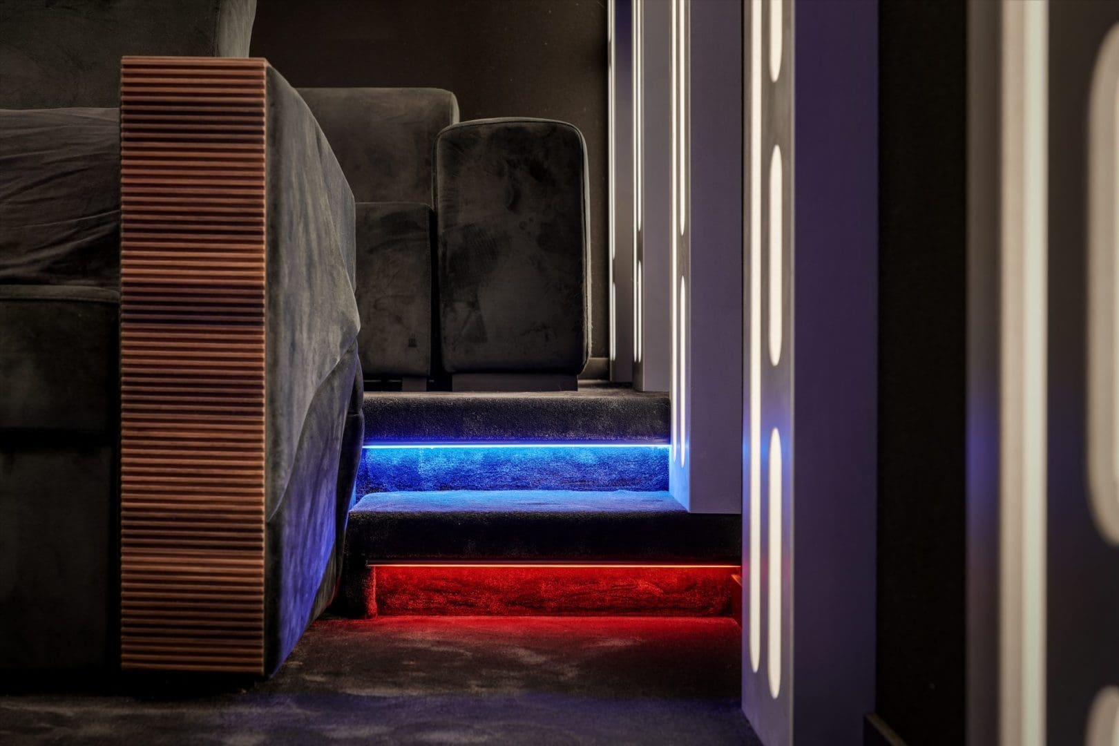 Fluwelen bank naast een verlichte trap met blauwe en rode ledstrips in een modern interieur genaamd Project Hyperspace 0.5. Fluwelen bank naast een verlichte trap met blauwe en rode ledstrips in een modern interieur genaamd Project Hyperspace 0.5.