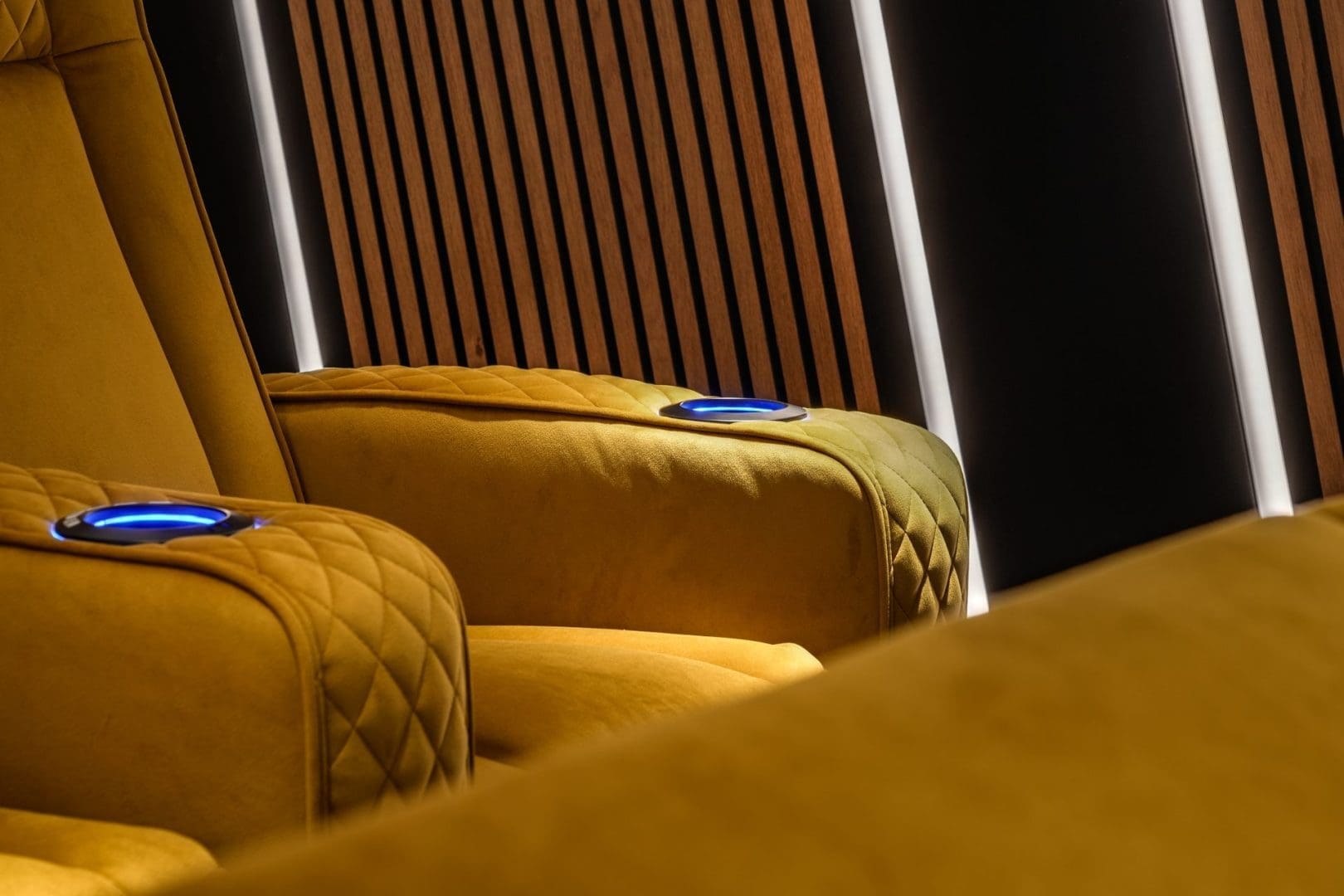 Gele fluwelen bioscoopstoelen met blauw verlichte bekerhouders voor een wand met houten latten uit Project Apex 0.5. Gele fluwelen bioscoopstoelen met blauw verlichte bekerhouders voor een wand met houten latten uit Project Apex 0.5.