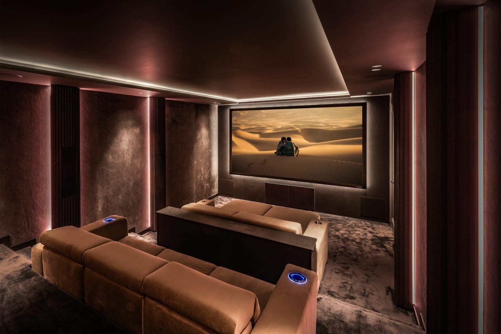 Luxe thuisbioscoop met bruine banken en een groot scherm waarop een woestijnlandschap te zien is in Project Opus 0.2. Luxe thuisbioscoop met bruine banken en een groot scherm waarop een woestijnlandschap te zien is in Project Opus 0.2.