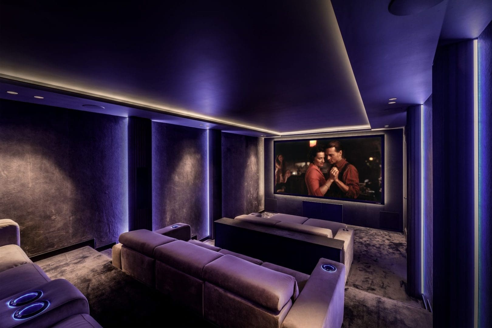 Luxe thuisbioscoop met paarse ledverlichting, comfortabele banken en een groot scherm met een dansend koppel.
