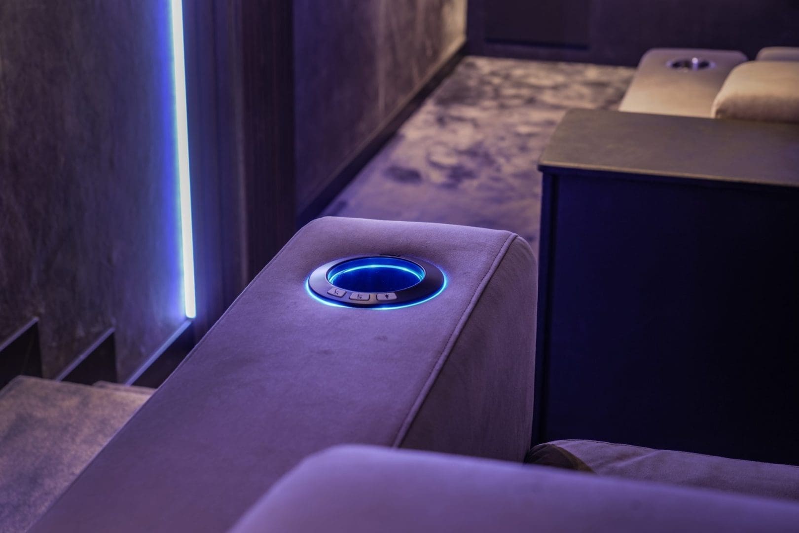 Grijze bioscoopstoel met een verlichte blauwe bekerhouder in een donkere kamer met sfeerverlichting, Project Opus 0.4. Grijze bioscoopstoel met een verlichte blauwe bekerhouder in een donkere kamer met sfeerverlichting, Project Opus 0.4.