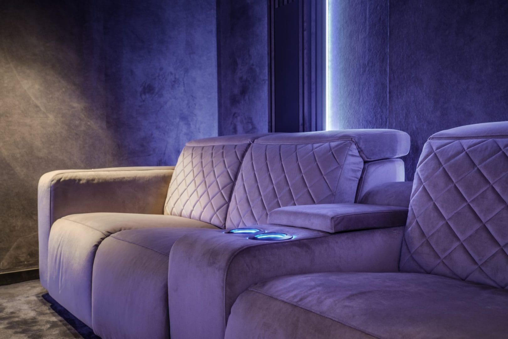 Luxe, paarse fluwelen bioscoopbank met ruitpatroon en verlichte bekerhouders in een modern interieur genaamd Project Opus 0.5 Luxe, paarse fluwelen bioscoopbank met ruitpatroon en verlichte bekerhouders in een modern interieur genaamd Project Opus 0.5