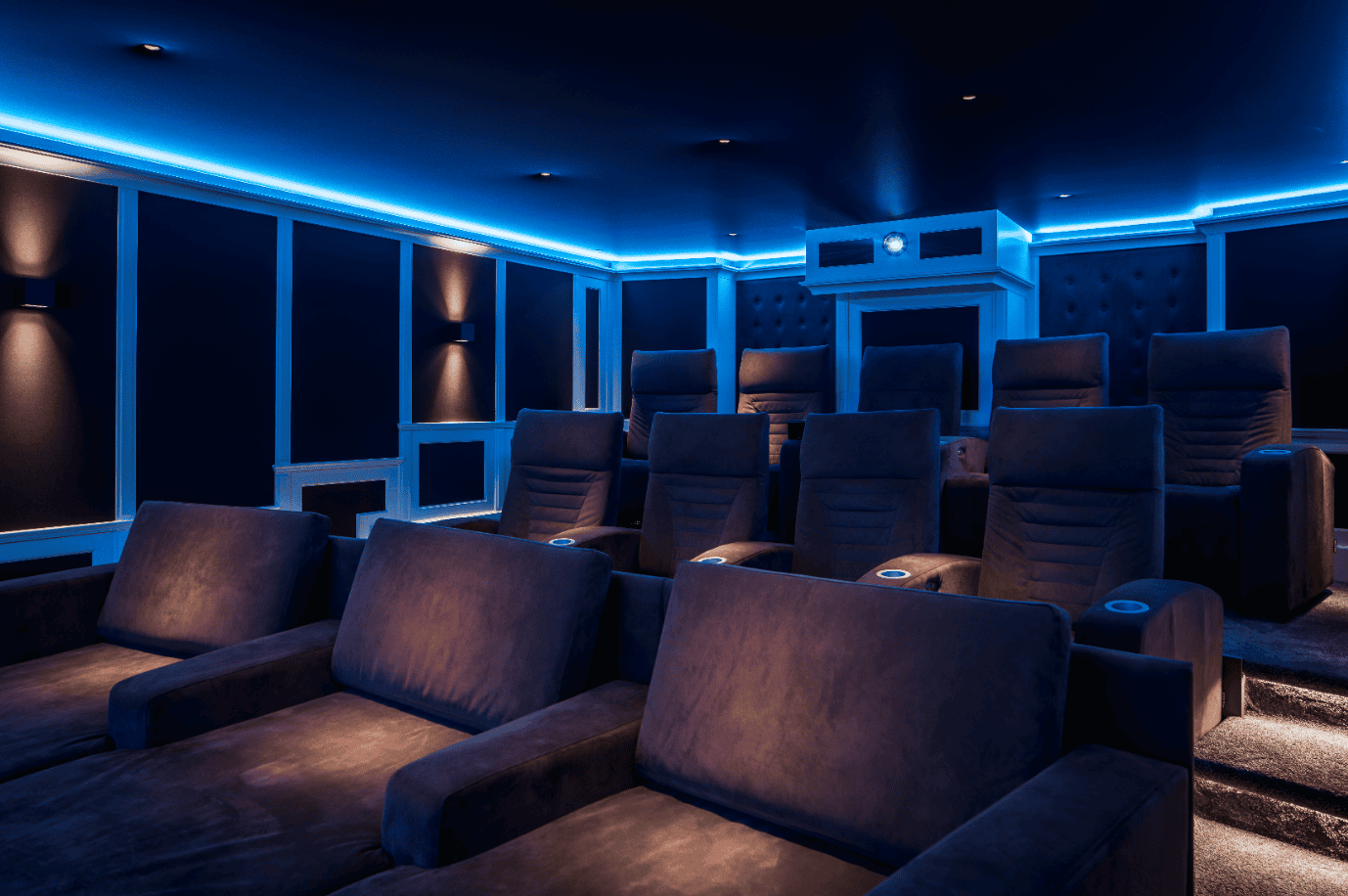 Luxe thuisbioscoop met rijen comfortabele stoelen, sfeervolle blauwe ledverlichting en een ingebouwde projector.