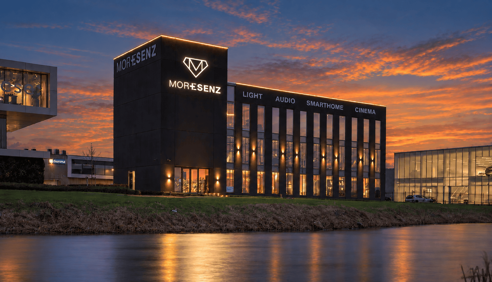 Verlicht bedrijfspand van MoreSenz met de teksten Light, Audio, Smarthome en Cinema aan de gevel bij zonsondergang. Verlicht bedrijfspand van MoreSenz met de teksten Light, Audio, Smarthome en Cinema aan de gevel bij zonsondergang.
