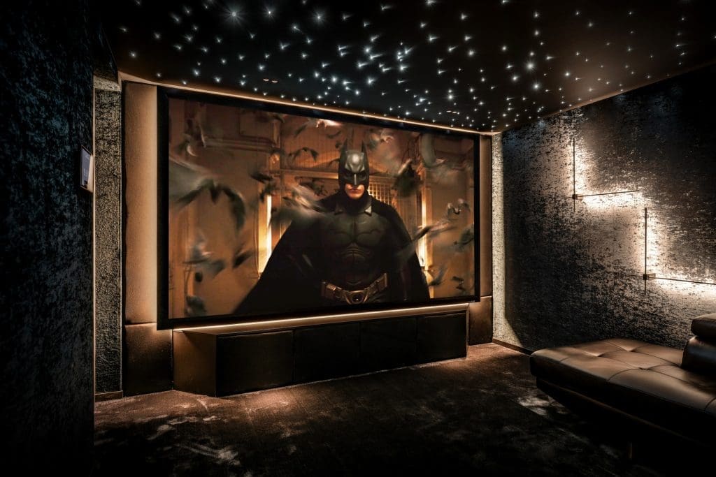 Thuisbioscoop met een groot scherm waarop Batman te zien is, onder een plafond met sterrenhemelverlichting.